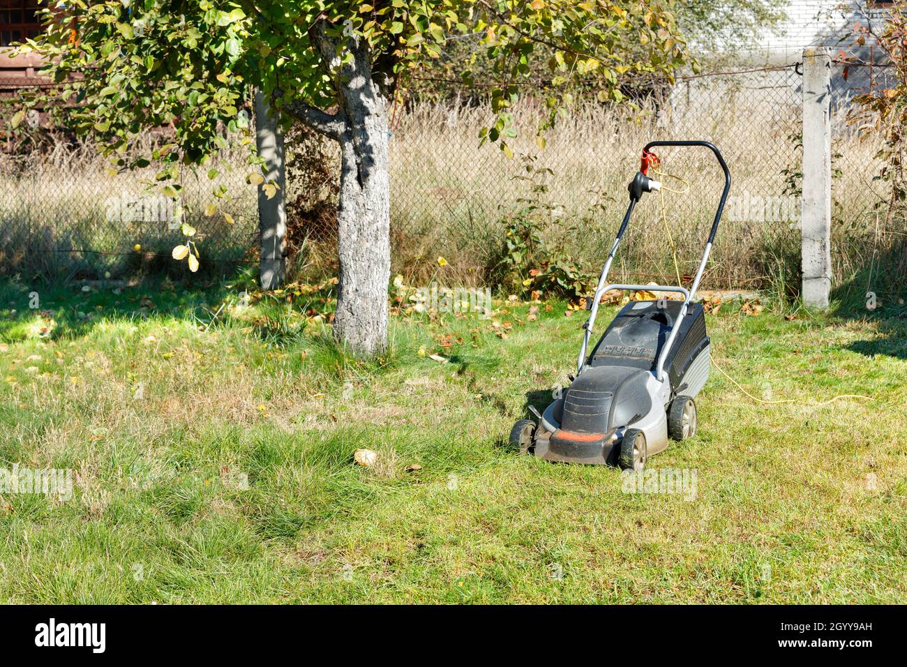 The electric lawnmower is ready to go and stands on a green lawn of a