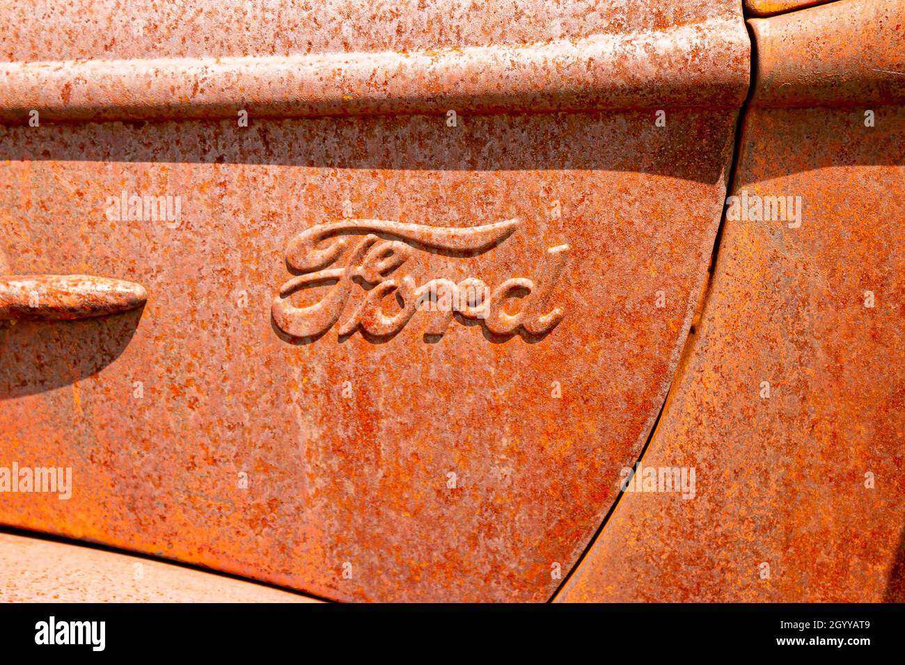 rusty vintage Ford logo on truck in junkyard Stock Photo
