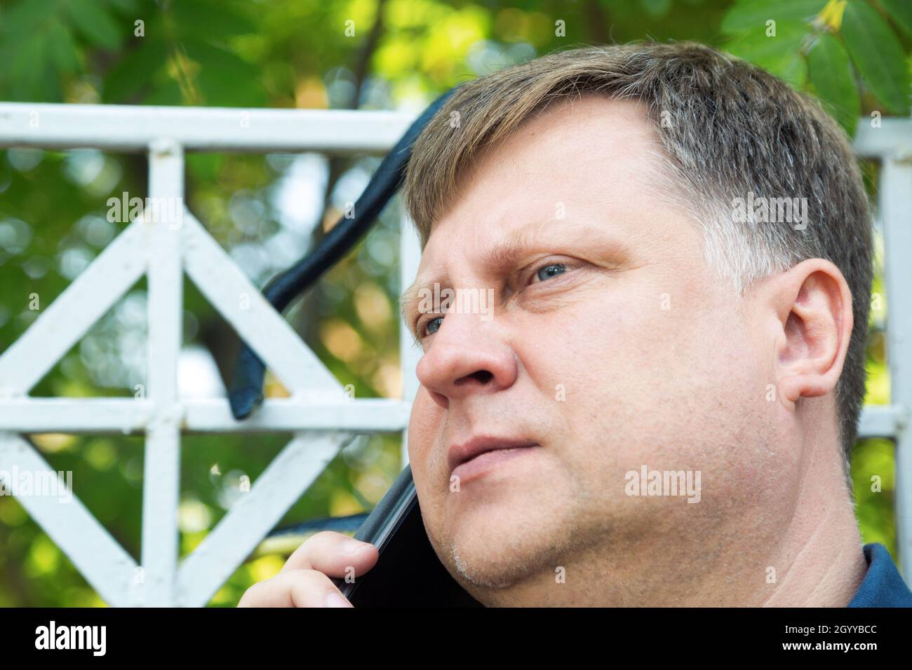 A black dangerous snake on a fence in the park near an adult man ...