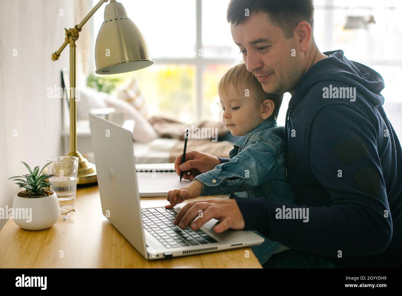 Father freelancer or business man with baby boy at desk at home office.  Working from home Stock Photo - Alamy