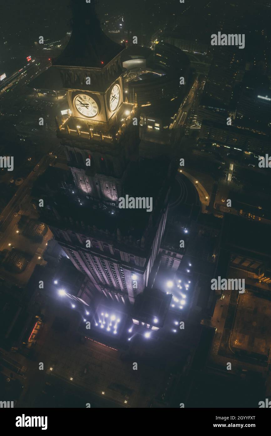 Notable high-rise building Palace of Culture and Science covered in fog, lit by colored lights, night city aerial panorama Stock Photo