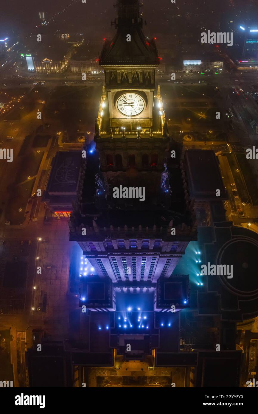 Notable high-rise building Palace of Culture and Science covered in fog, lit by colored lights, night city aerial panorama Stock Photo