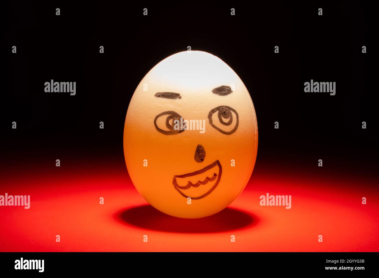 smiling egg face highlighted in dark Stock Photo