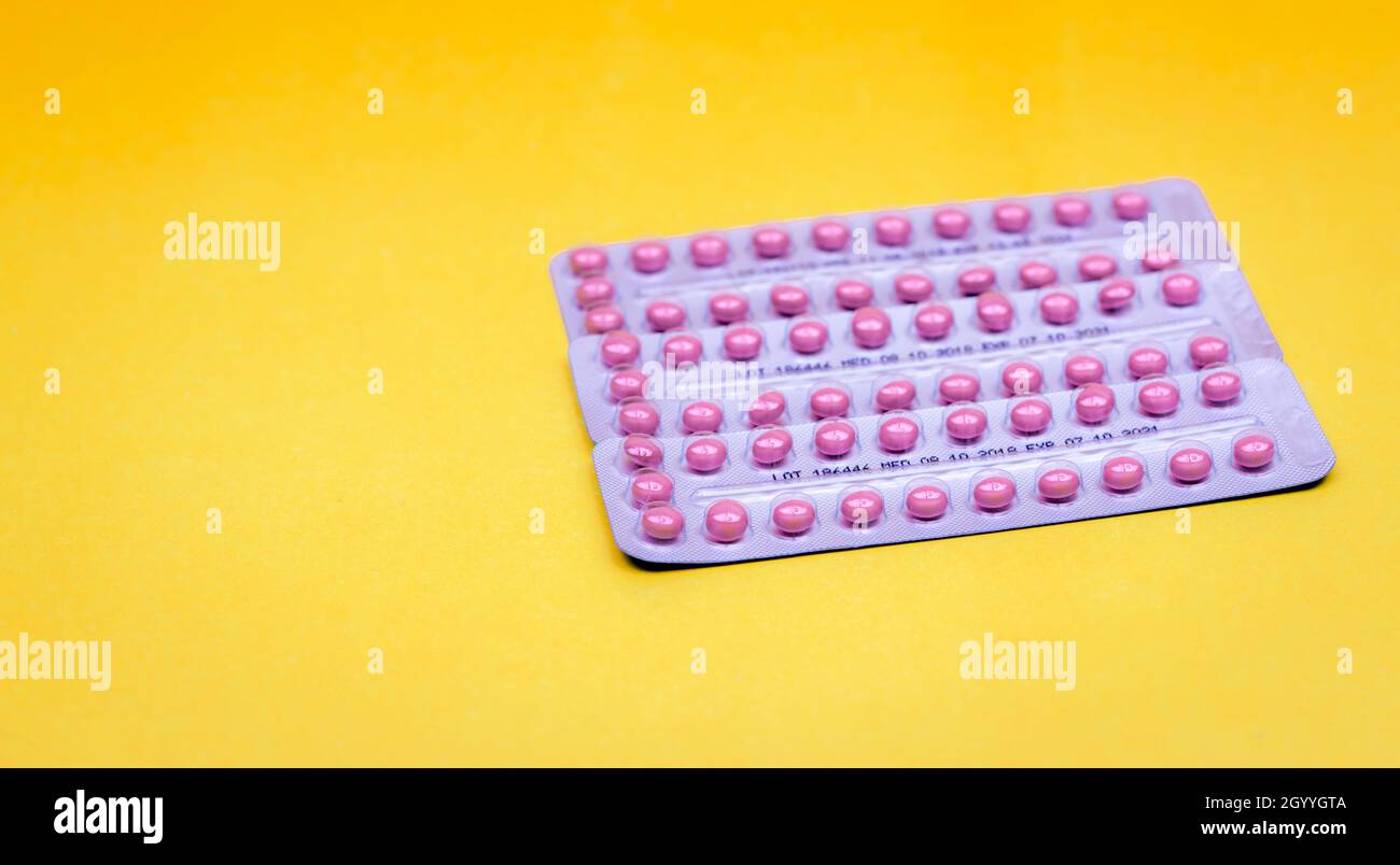 Blister packs of contraceptive pills on yellow background. Hormone pills for treatment hormone acne. Birth control pills. Estrogen and progesterone Stock Photo