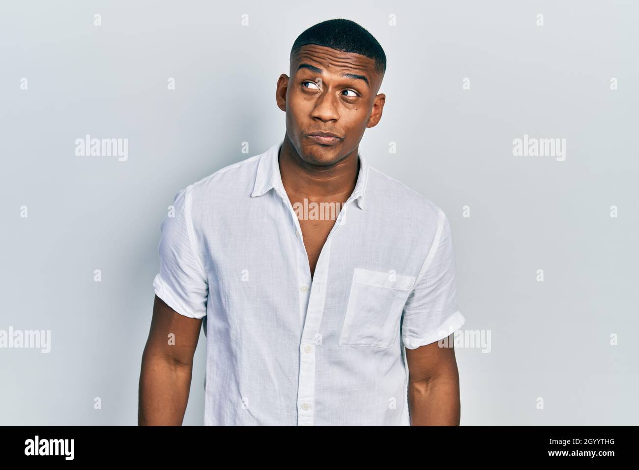 Young black man wearing casual white shirt smiling looking to the side ...