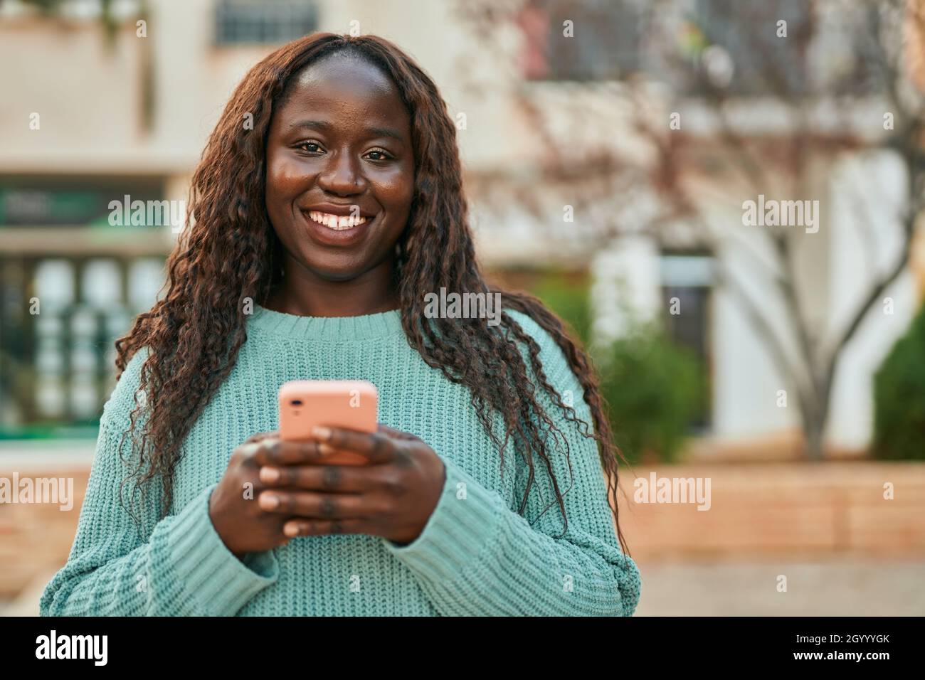 Young african woman smiling happy using smartphone at the city Stock ...