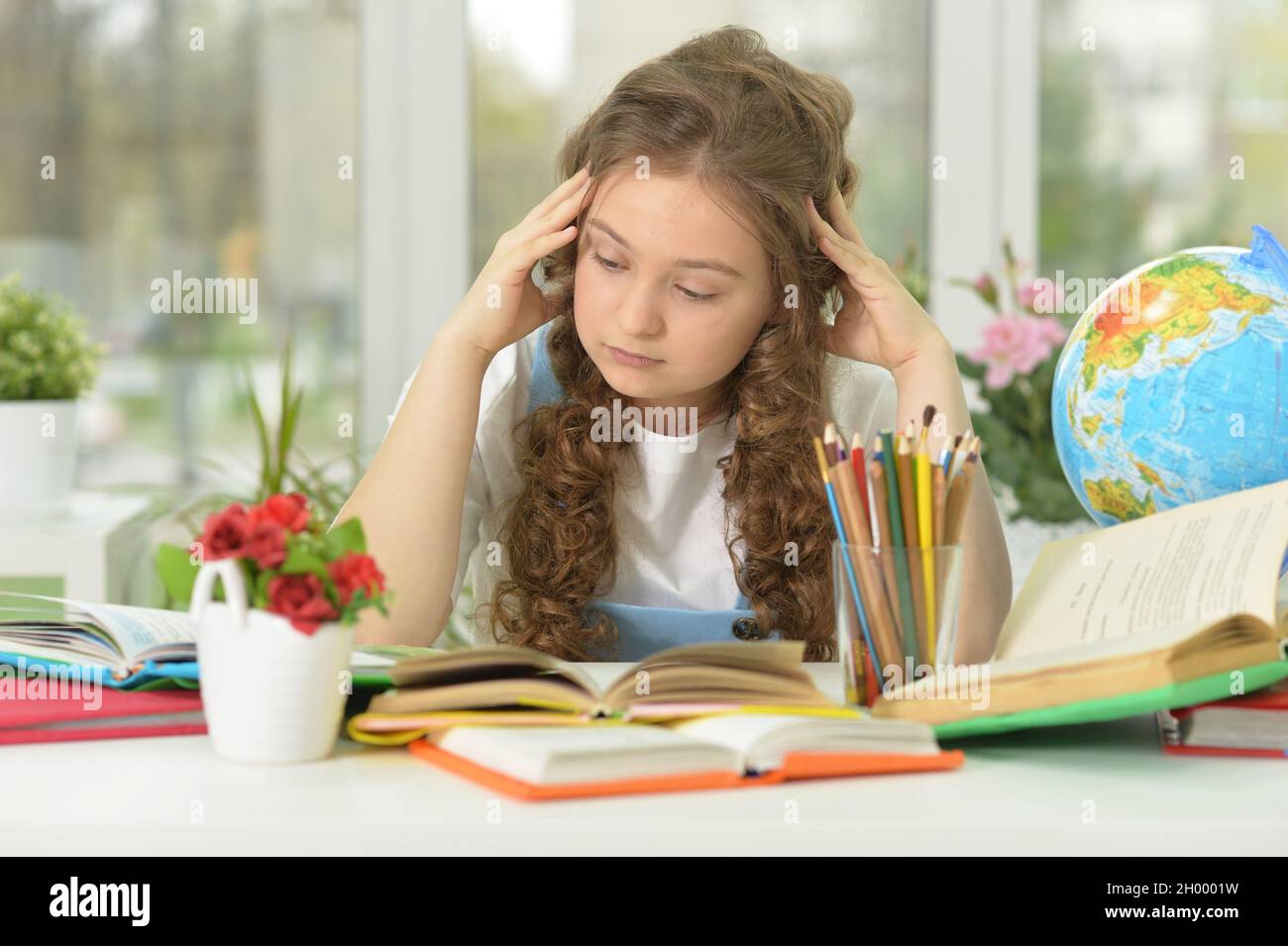 Girl siting at table studying, doing home work Stock Photo - Alamy