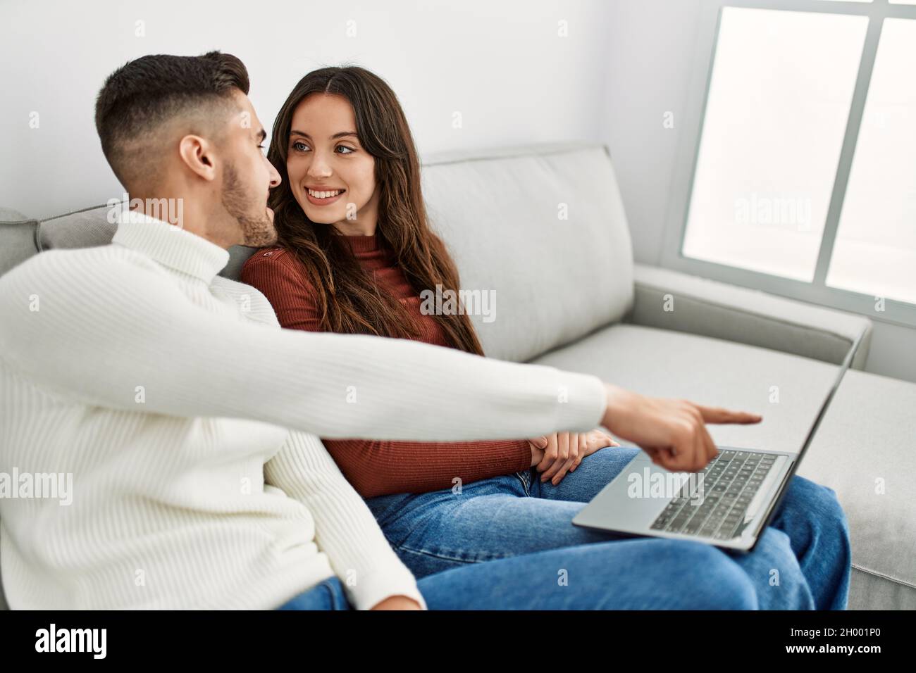 Young hispanic couple using laptop sitting on the sofa at home Stock ...