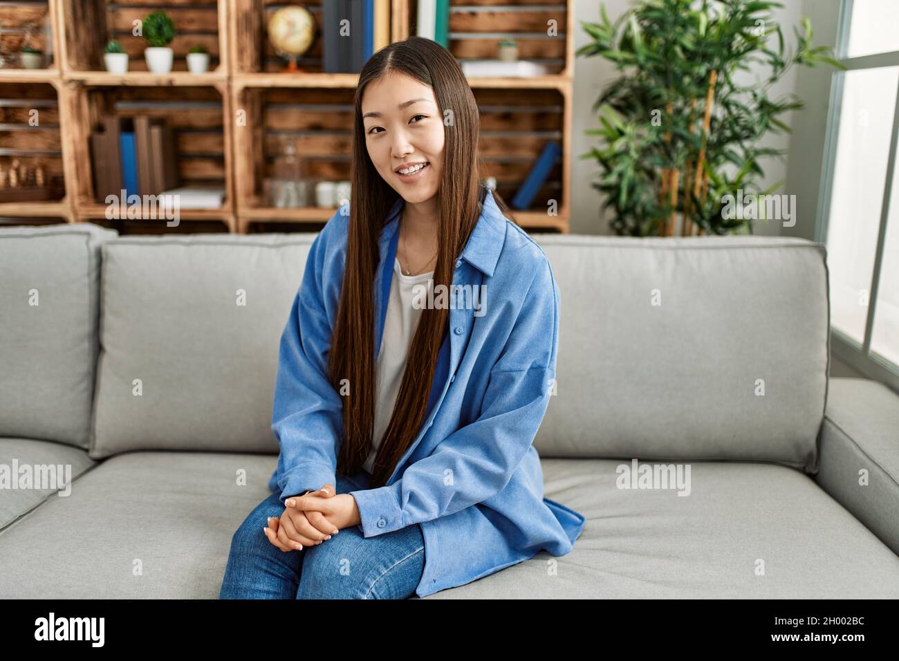 Young chinese girl smiling happy sitting on the sofa at home Stock ...