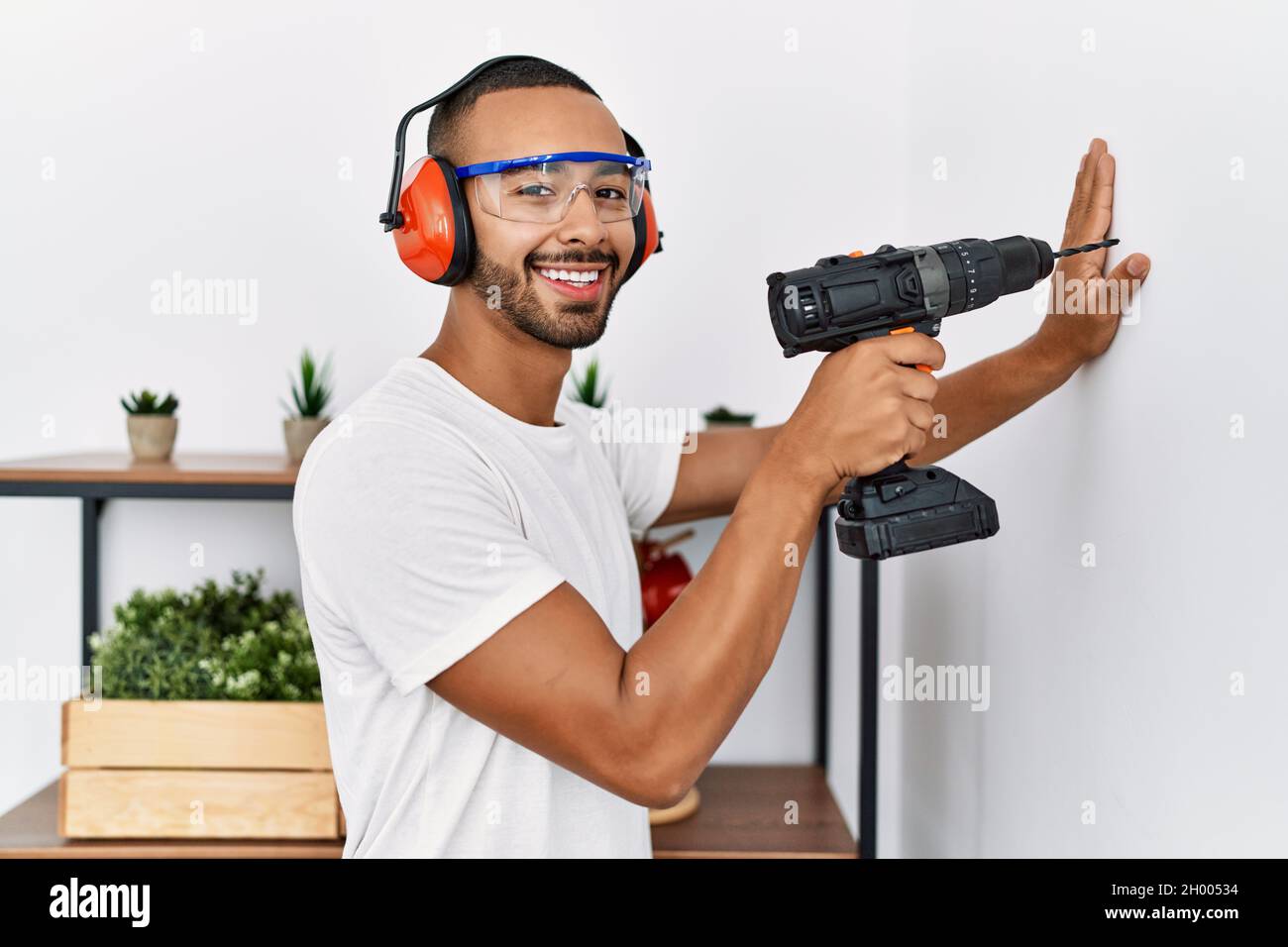 Young hispanic man smiling confident using drill at home Stock Photo