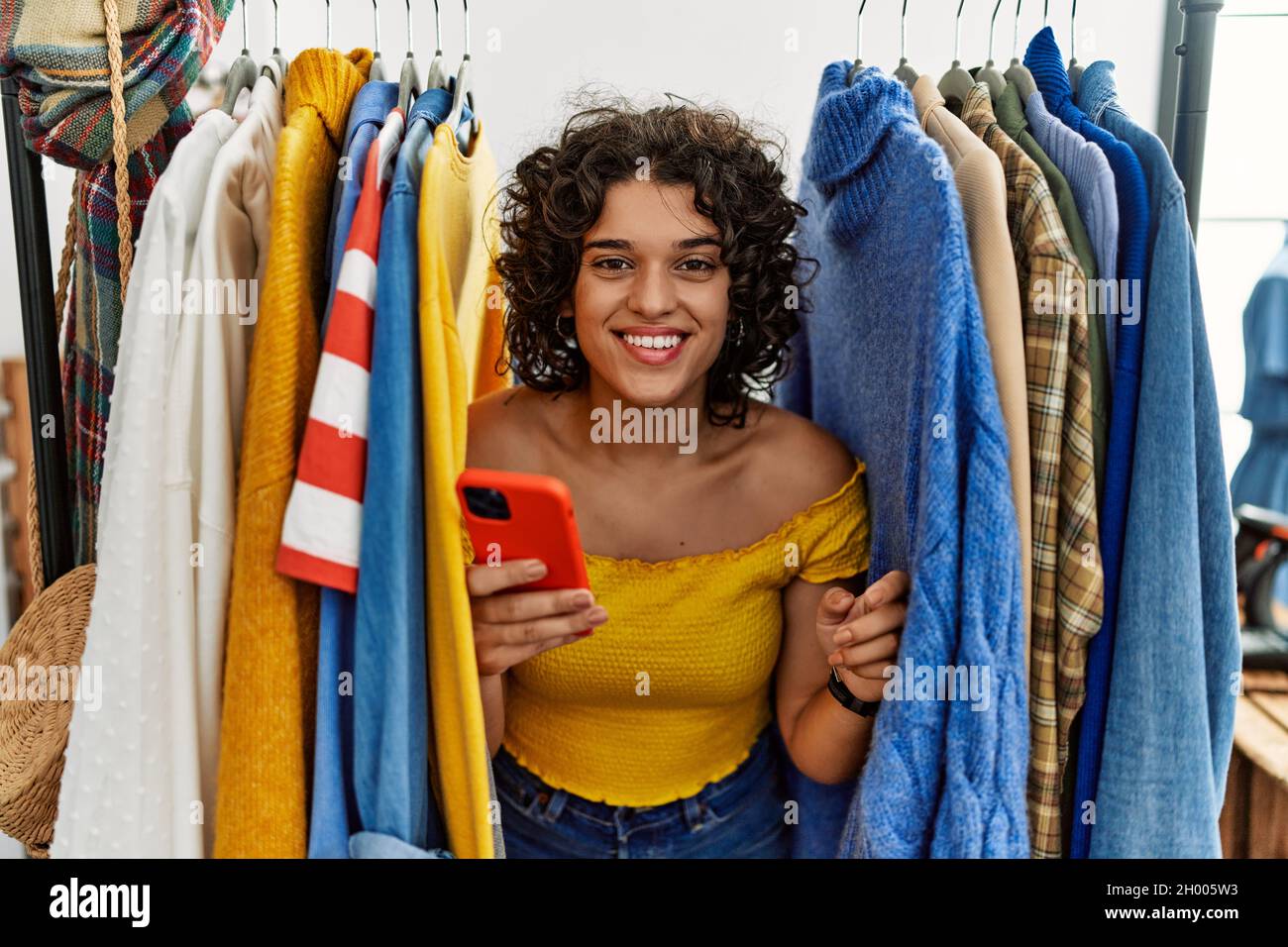 Hispanic Rack Young hispanic woman searching clothes on clothing rack using ...