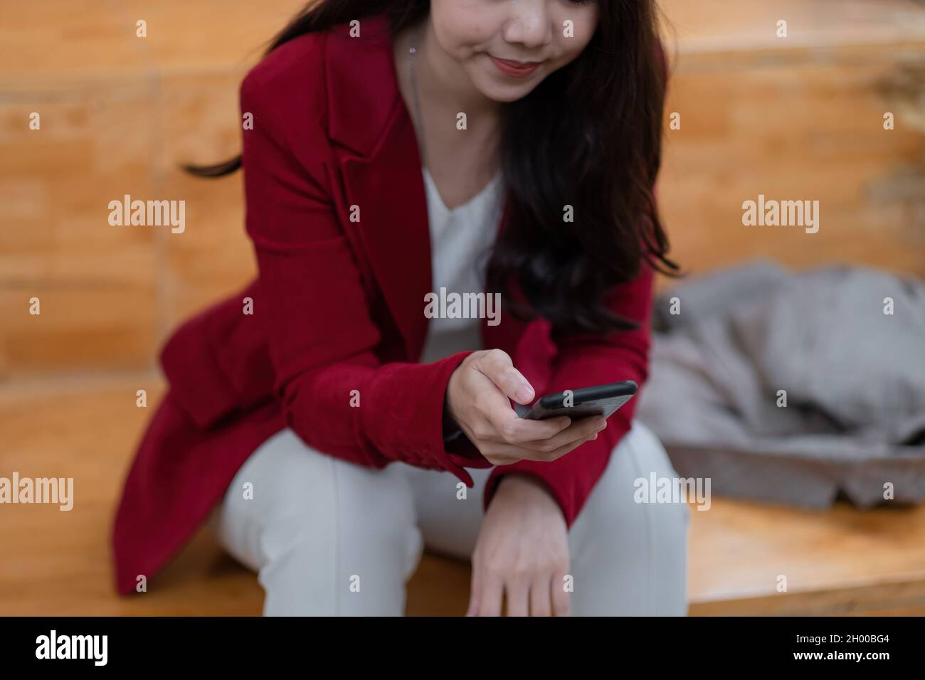 Cropped shot of asian woman using smart phone at home. messaging or browsing social networks Stock Photo
