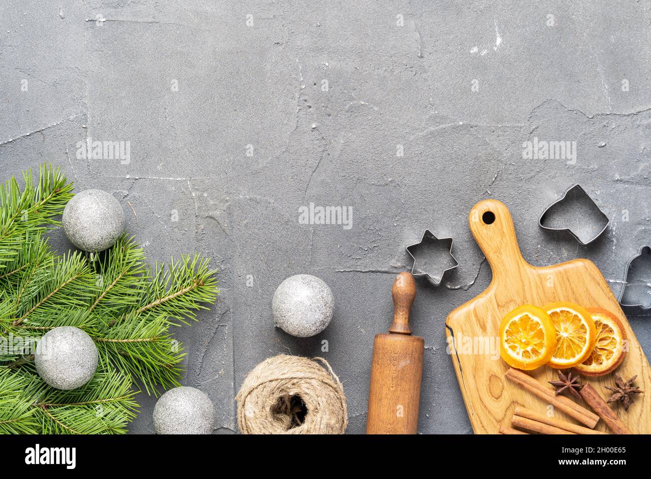 Green branches of the Christmas tree, oranges, ingredients for ginger cookies on a gray background, merry Christmas and New Year. Top view Stock Photo