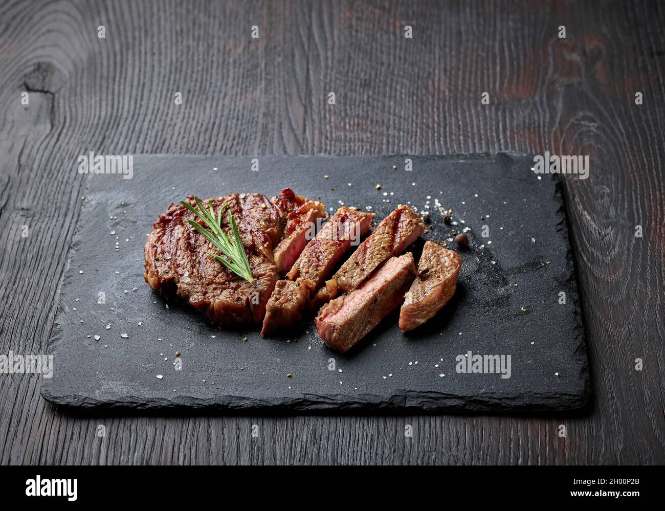 Sliced grilled entrecote steak on black stone board Stock Photo - Alamy