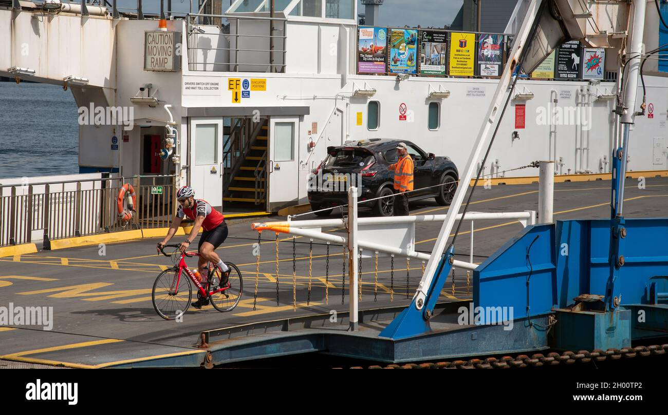 Torpoint, Cornwall, England, UK. 2021. Car loading and   pedal cyclist unloading from a roll on rool off chain ferry which crosses the River Tamar bet Stock Photo