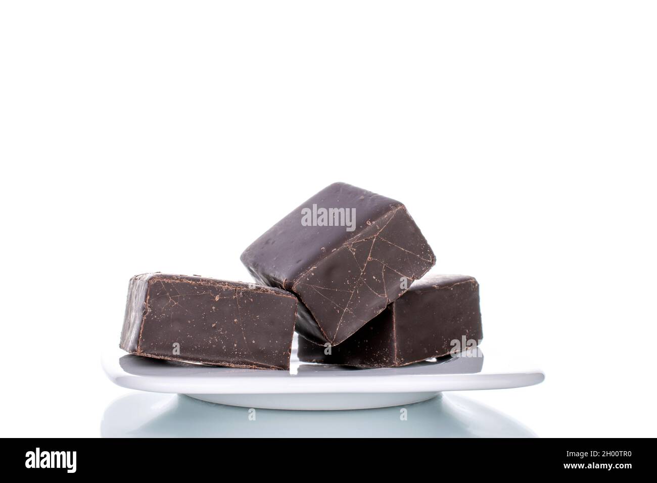 Several sweet chocolates with ceramic dishes, close-up, isolated on white. Stock Photo