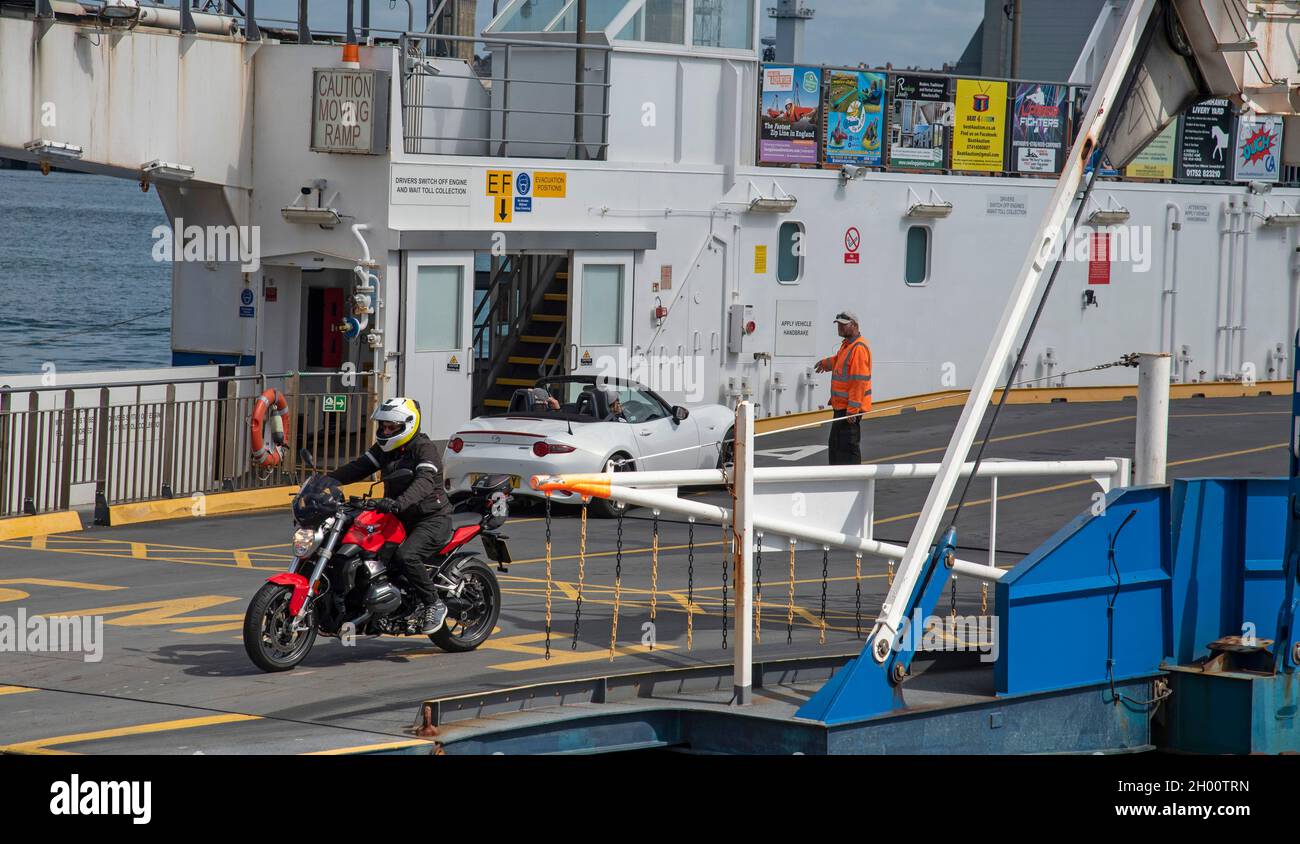 Torpoint, Cornwall, England, UK. 2021. Car loading and  motorcyclist unloading from a roll on rool off chain ferry which crosses the River Tamar betwe Stock Photo