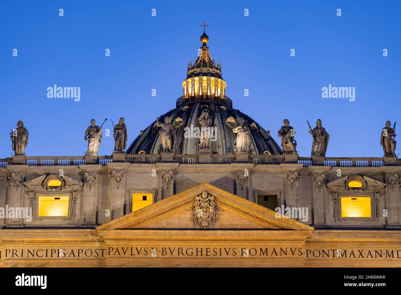 Dome, statues of Jesus and apostles and coat of arms in pediment of Saint Peter Basilica in Vatican city at dusk. Stock Photo