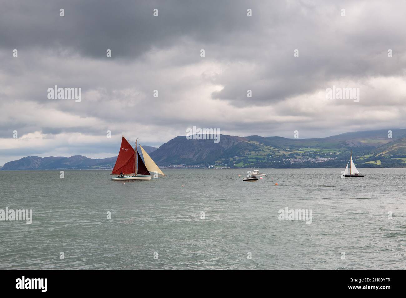 Beaumaris, Wales: Sailing boats on the Menai strait, with mountains of Snowdonia in the distance. Stock Photo