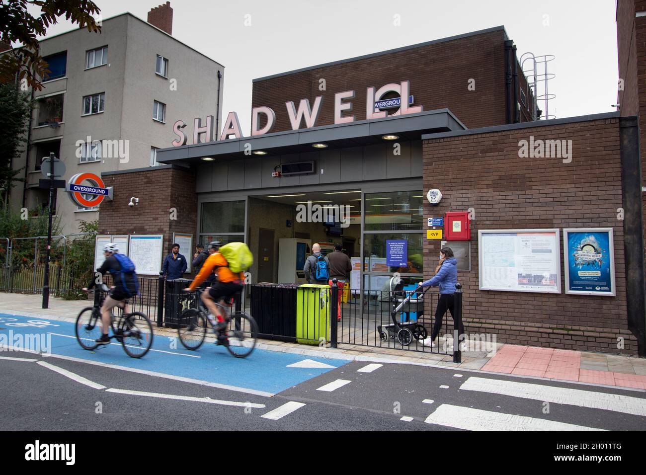 Shadwell DLR and overground station, London, with cyclists and pedestrians passing Stock Photo