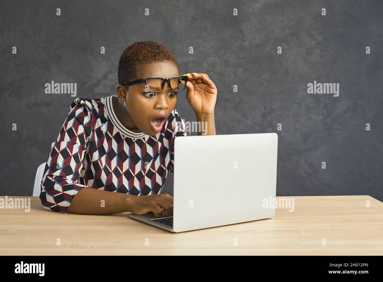 Shocked young African American woman looking open-mouthed at screen of her laptop Stock Photo
