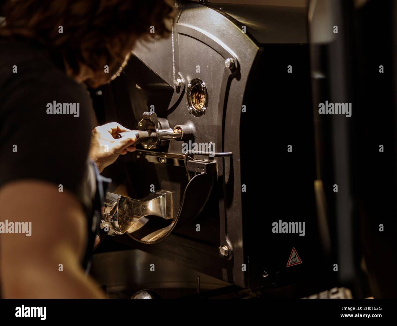 Man using industrial coffee roasting machine at factory Stock Photo