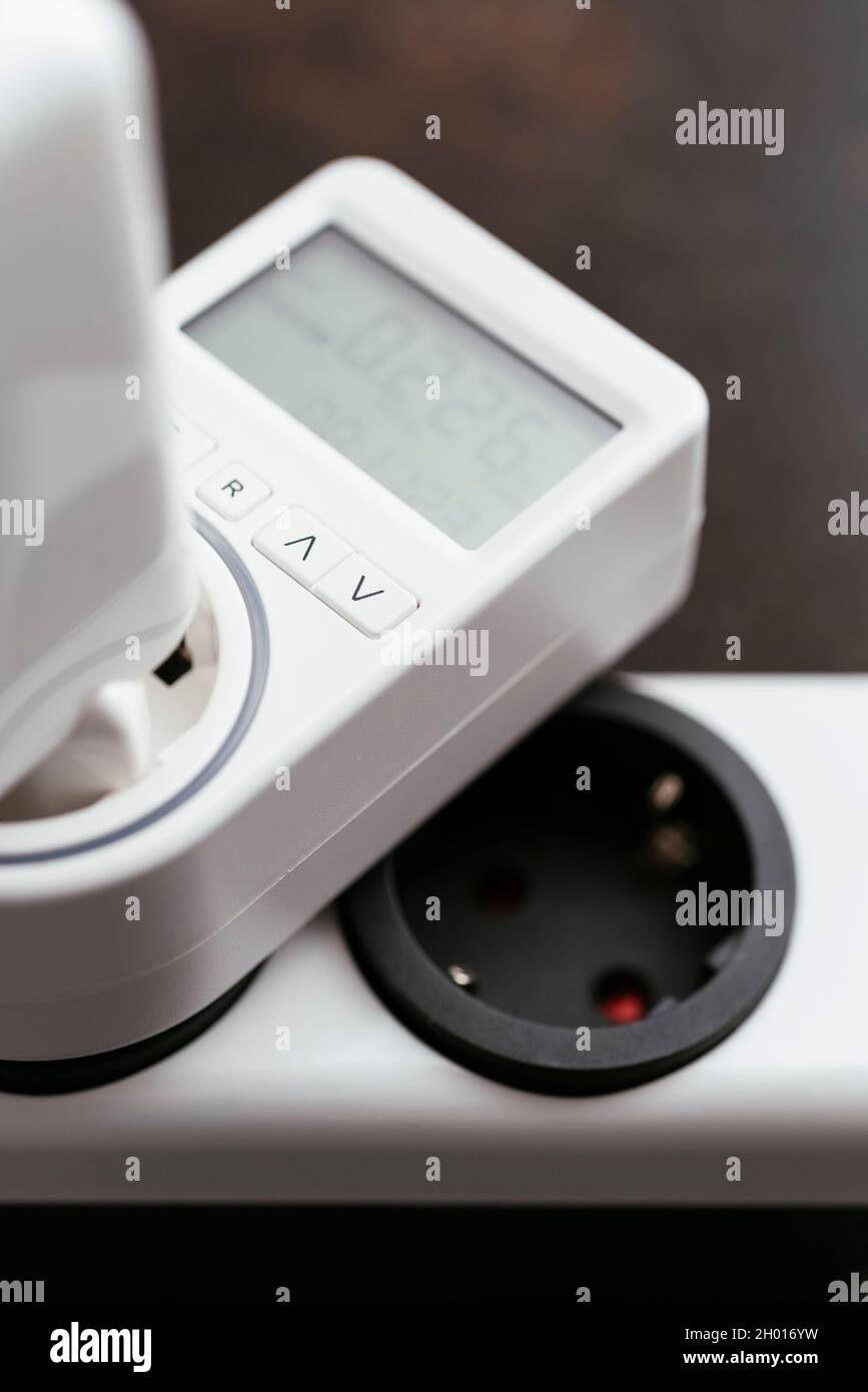 Electricity usage monitor measuring the standby power consumption of a laptop power supply. Stock Photo