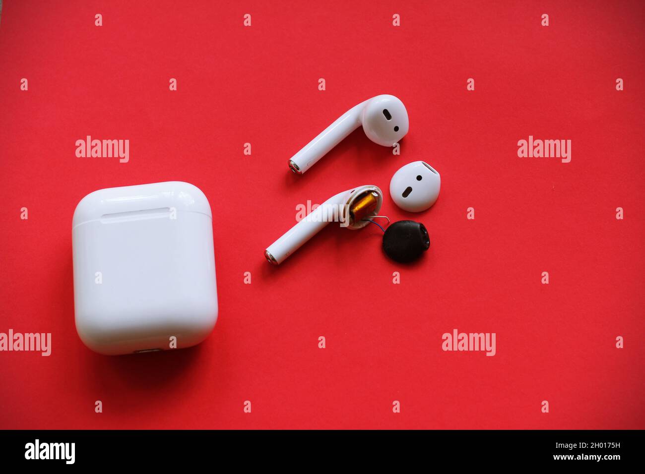 Shot of broken AirPods on a red background Stock Photo - Alamy