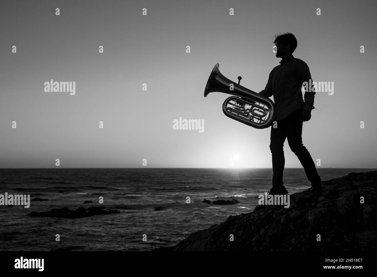 Silhouette of a musician man with a tuba on the sea coast. Black and white photo. Stock Photo