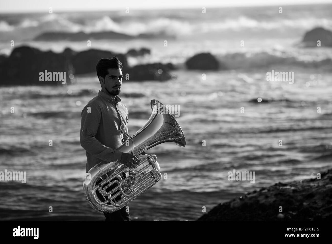 A musician man with a tuba on the Atlantic seashore. Black and white photo. Stock Photo