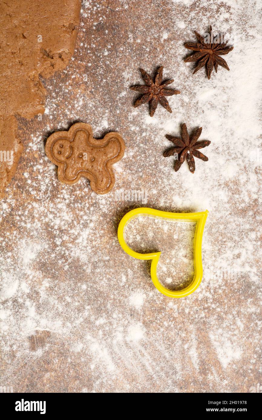 Gingerbread man cookie, three star anise fruits, cookie cutter in the shape of a heart and a piece of rolled out gingerbread sweet dough... Stock Photo
