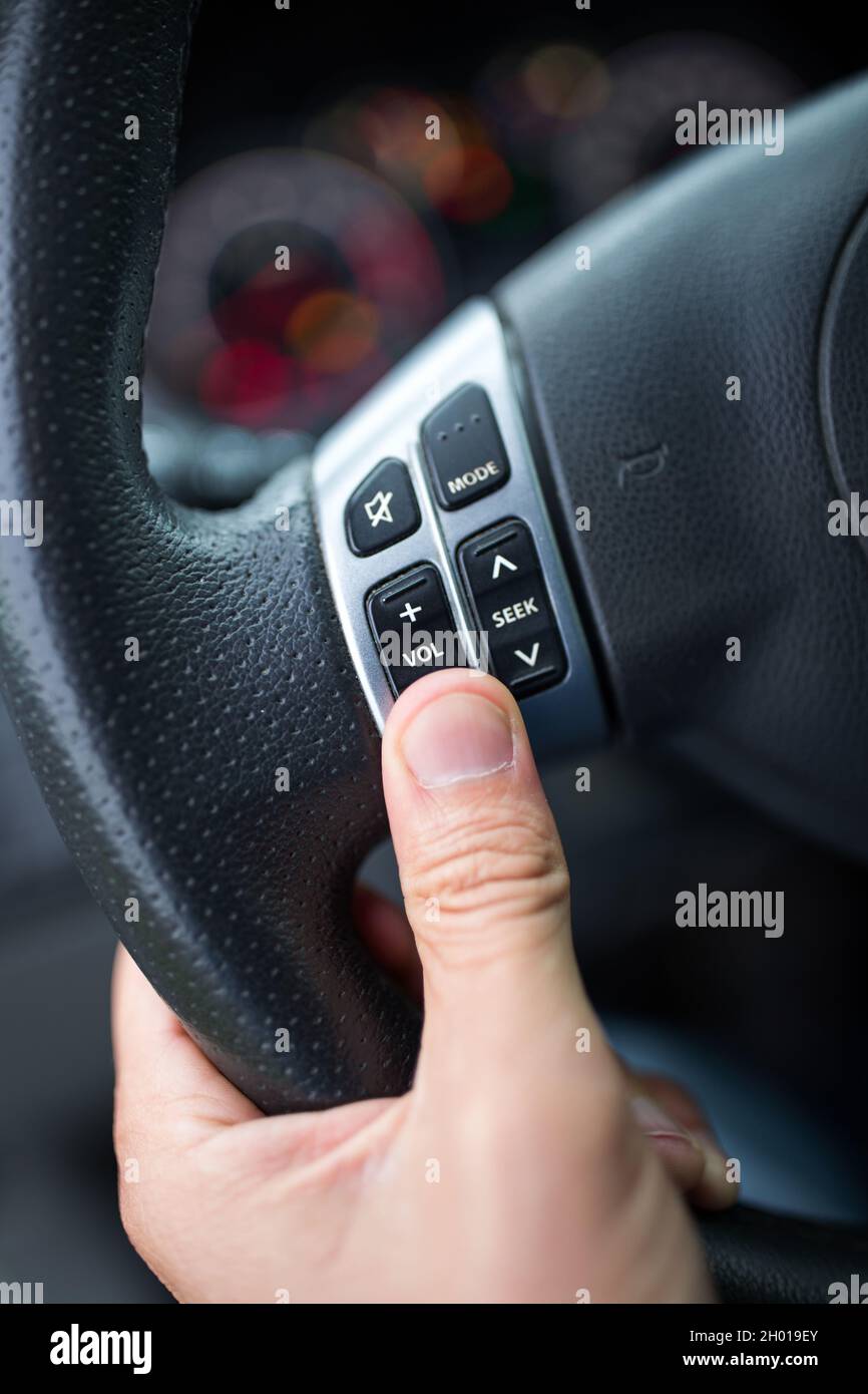 Close up of male hand holding volume control buttons on steering wheel in car Stock Photo Alamy