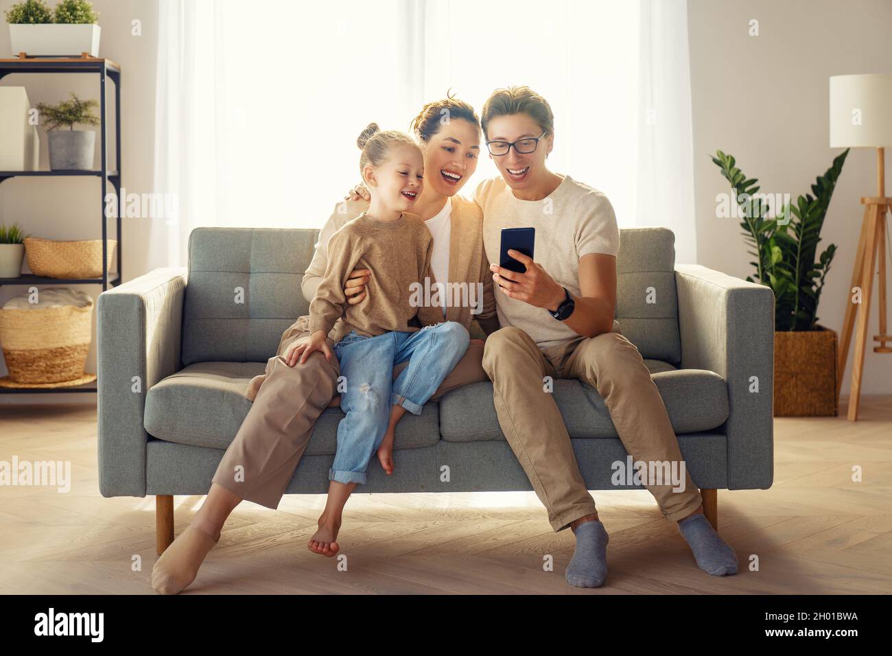 Happy loving family. Young mother, father and daughter using phone ...