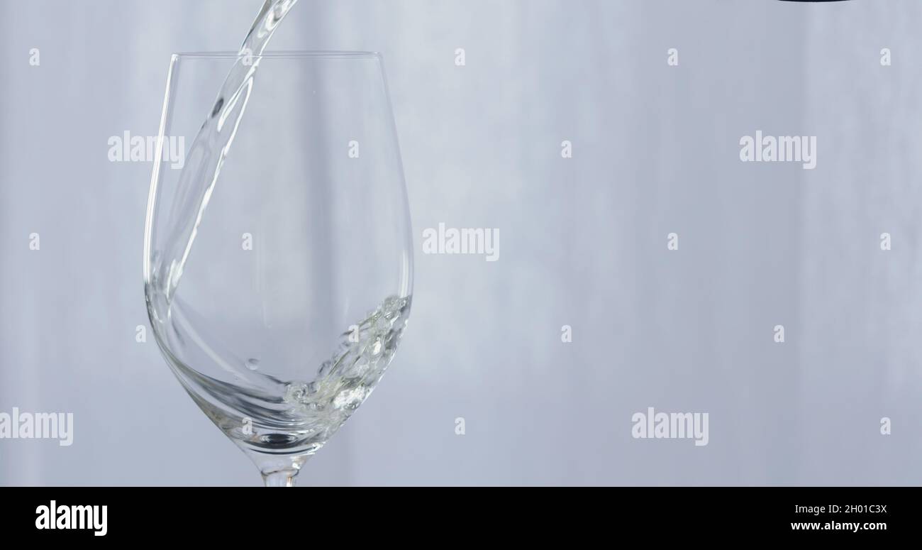 white wine pour into wineglass with curtains on background, wide photo Stock Photo