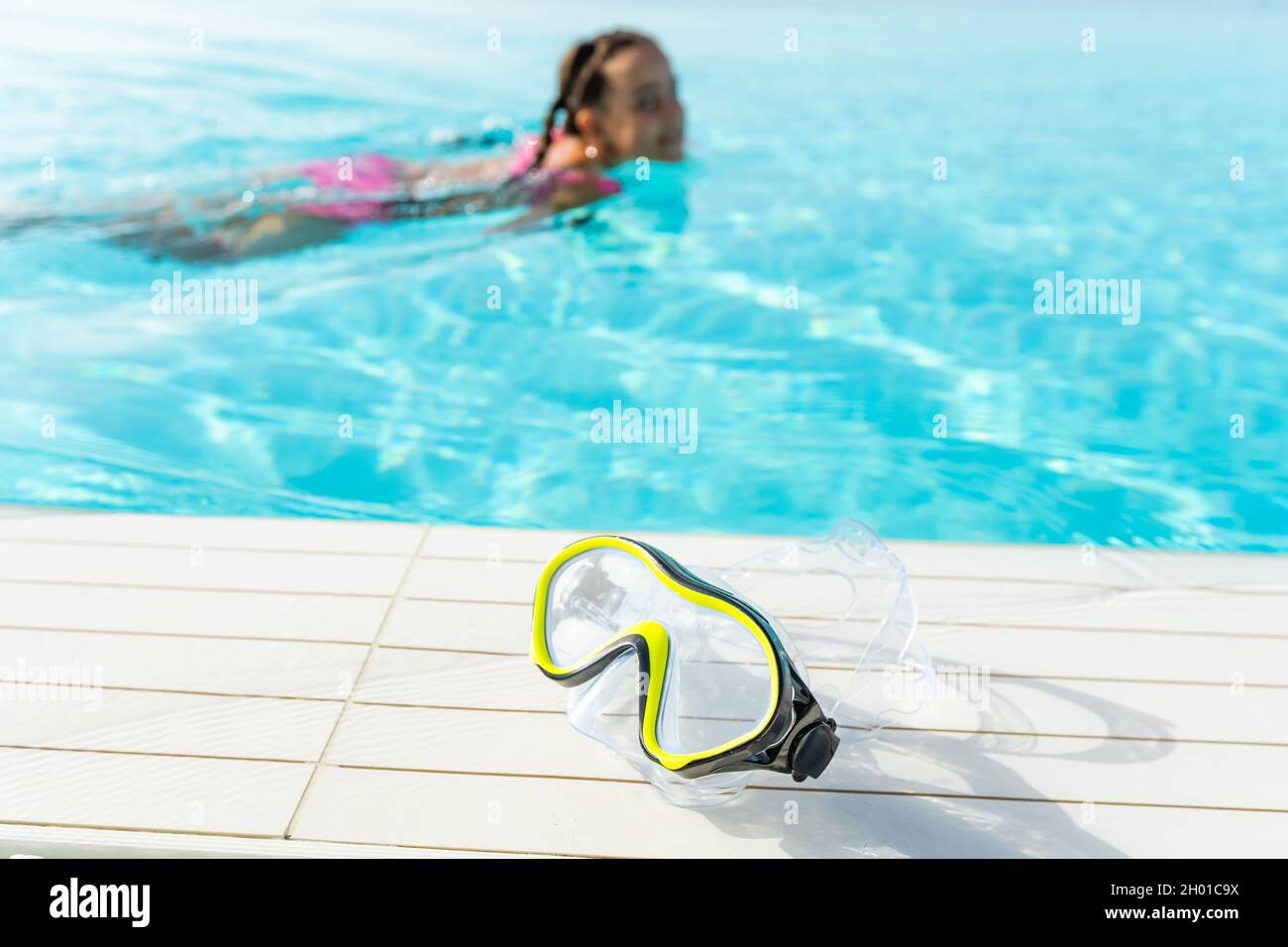 swimming mask with snorkel near the blue pool on a sunny tropical morning Stock Photo