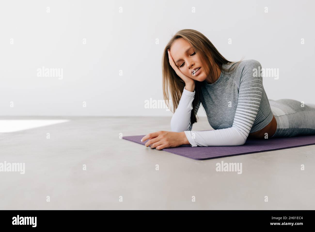 Portrait of a young fitness woman lying on a yoga mat and exercising ...