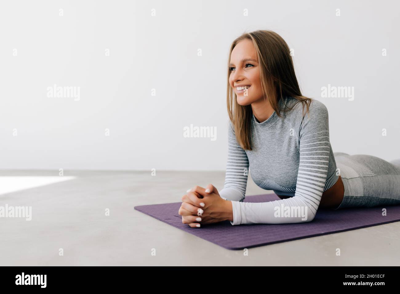 Portrait of a young fitness woman lying on a yoga mat and exercising ...