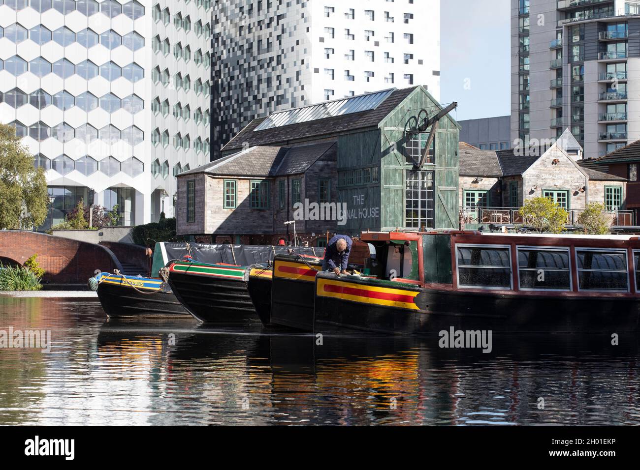 A man carrying out maintenance on his narrowboat at Gas Street canal basin in Birmingham, UK Stock Photo