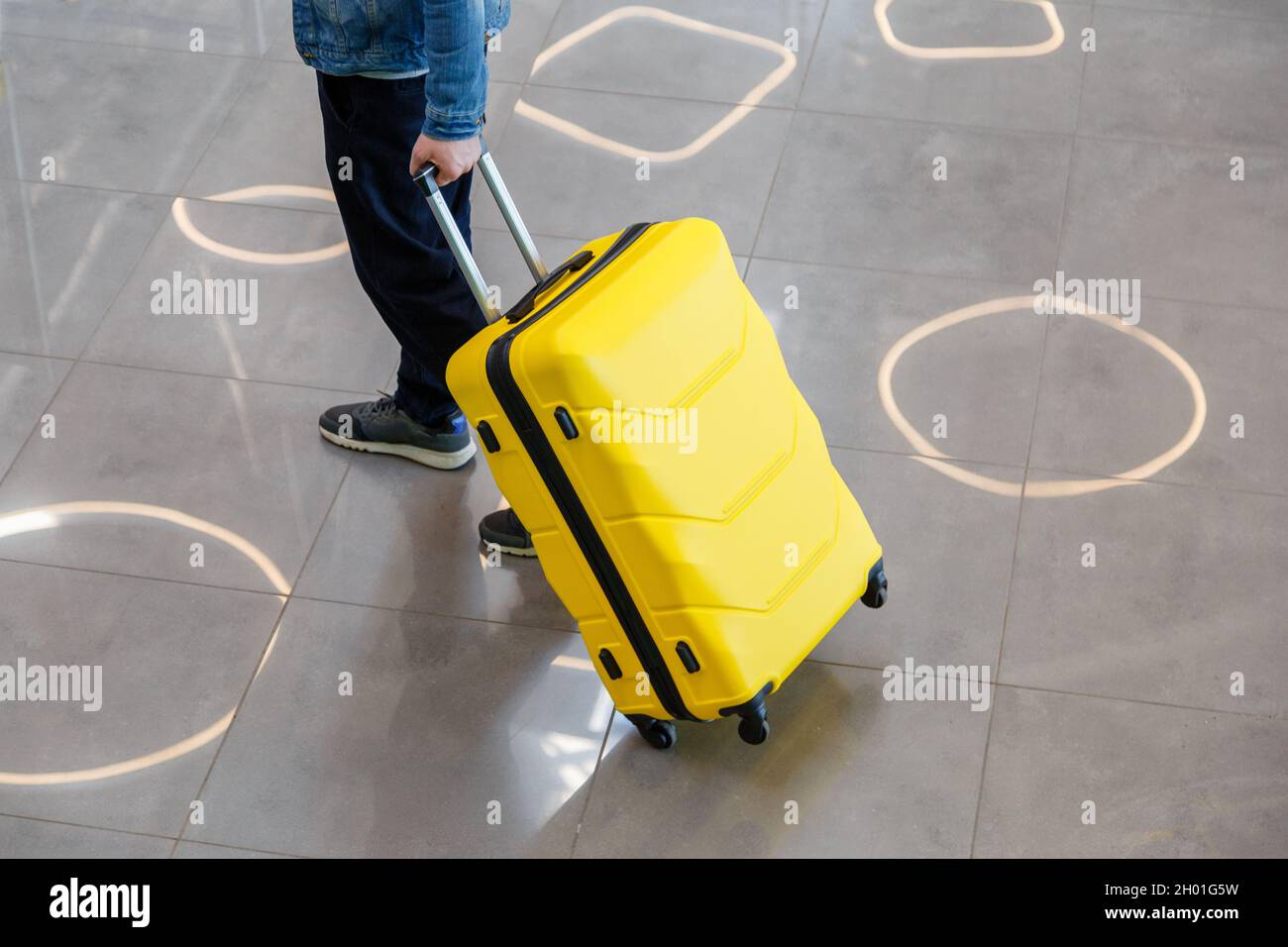 Large yellow suitcase luggage in male hands on the way to the train station. A man walks through the airport and carries a yellow large suitcase Stock Photo