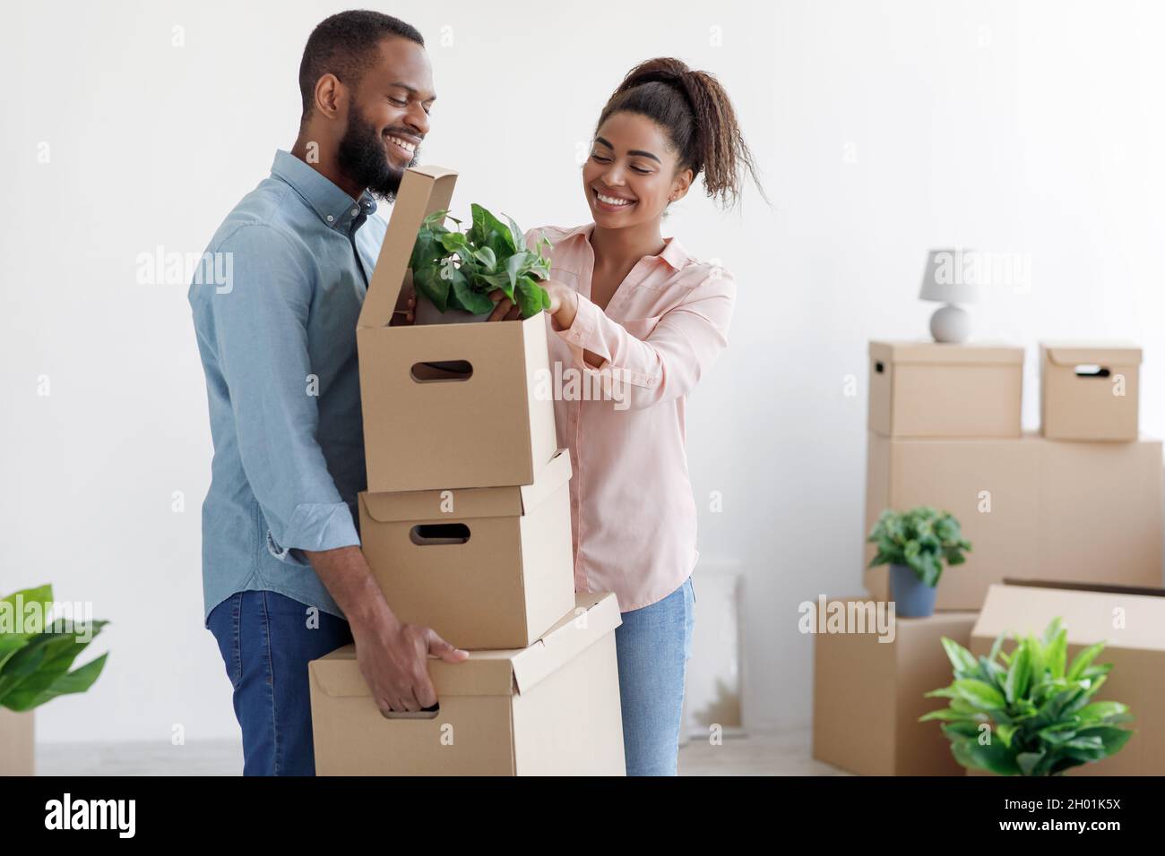 Glad millennial african american husband and wife unpacking boxes, take ...