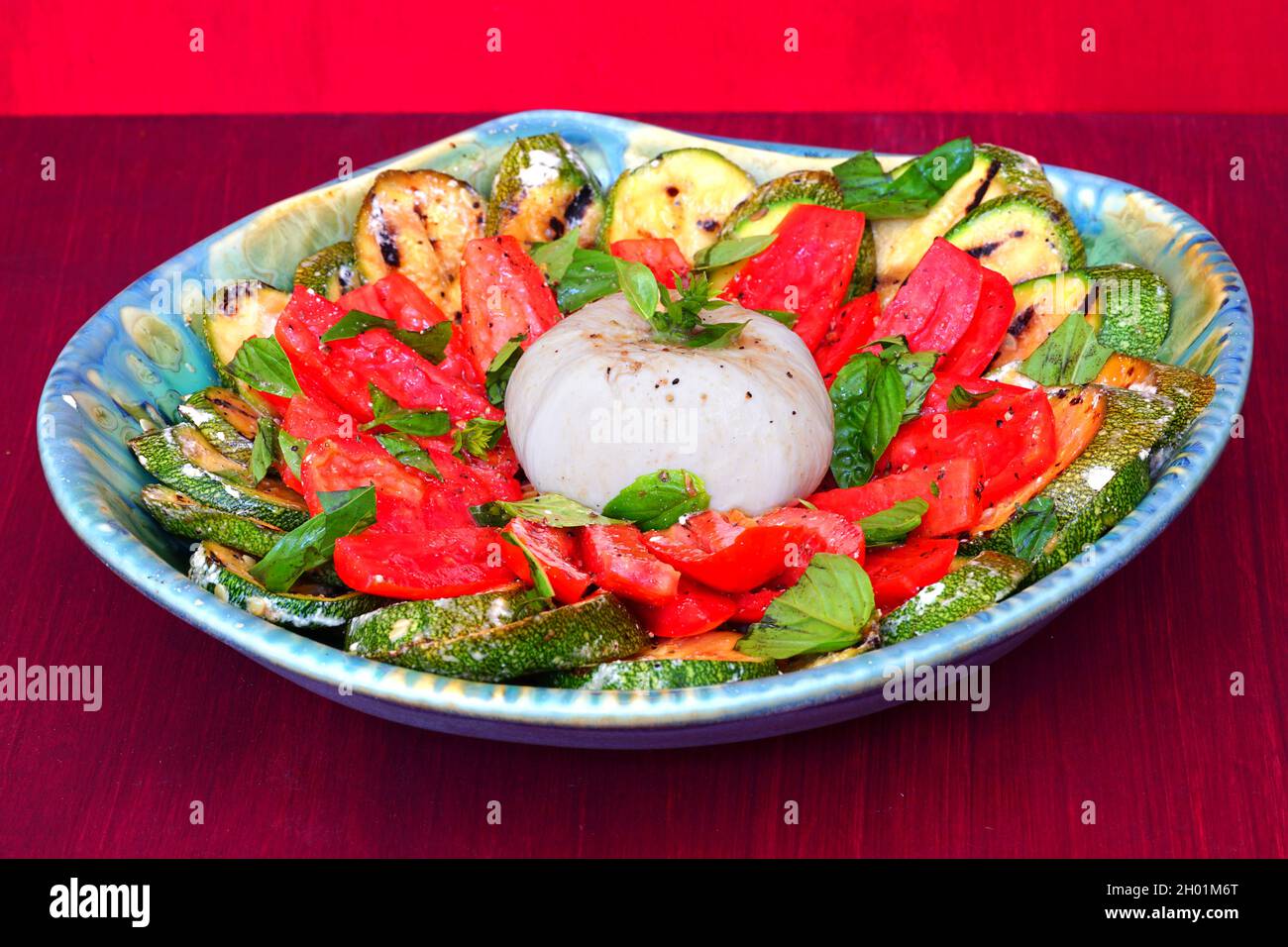 Dish of burrata cheese salad with fresh tomatoes and grilled zucchini