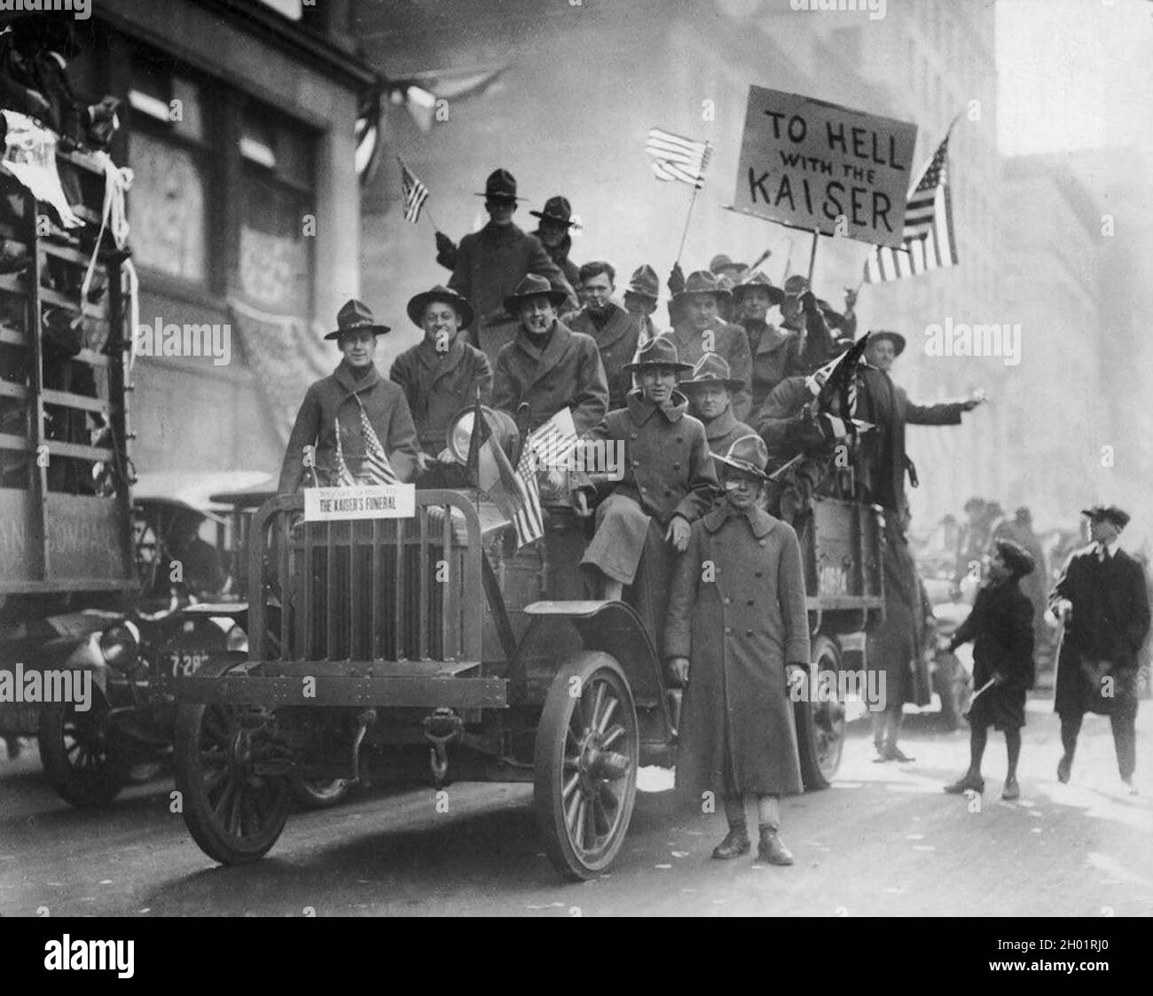 A group of American soldiers riding on a truck, waving American flags during an Armistice Day parade , New York City. Stock Photo