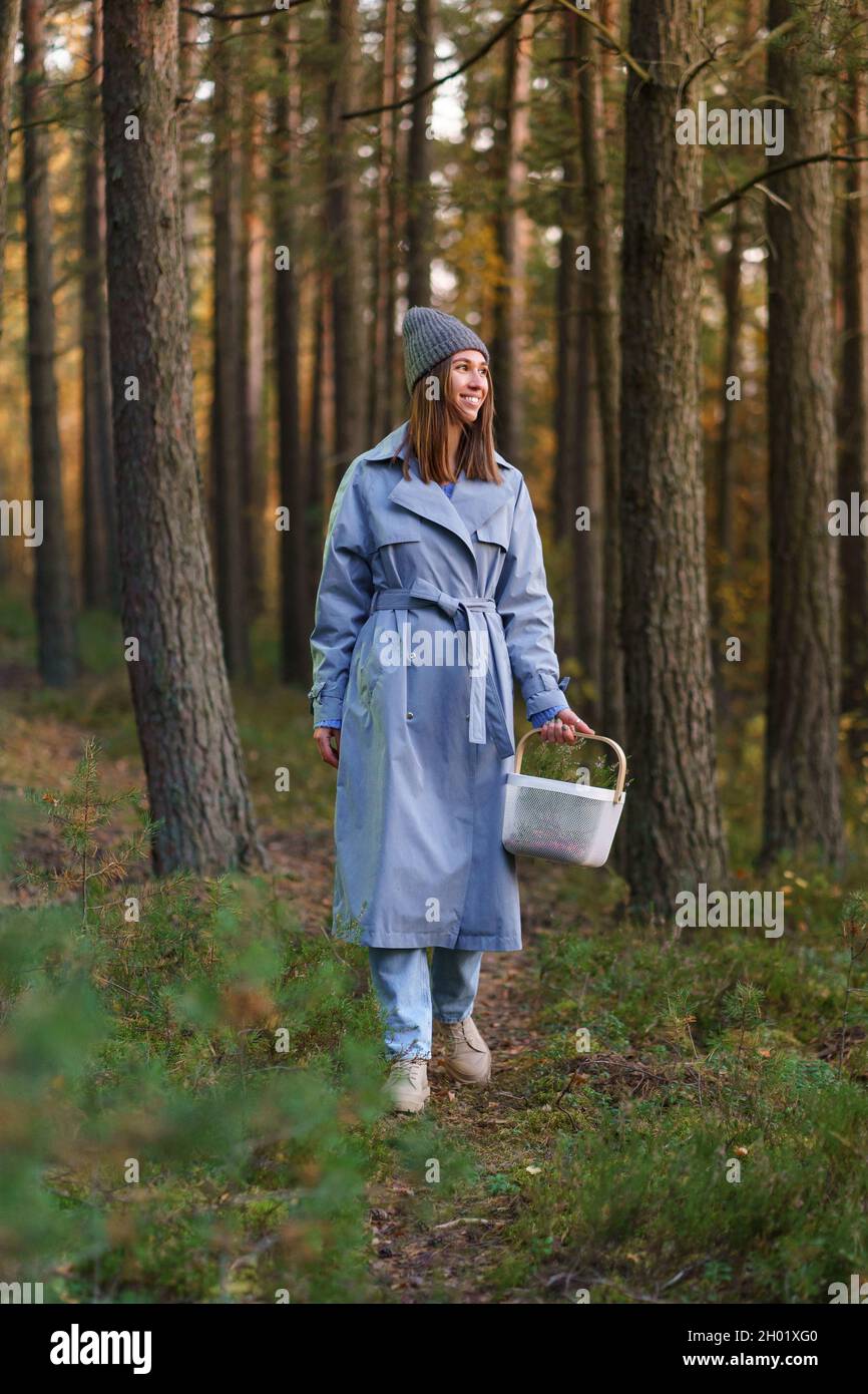 Picking season in forest: young woman spend day outdoor wondering searching for mushroom and berries Stock Photo