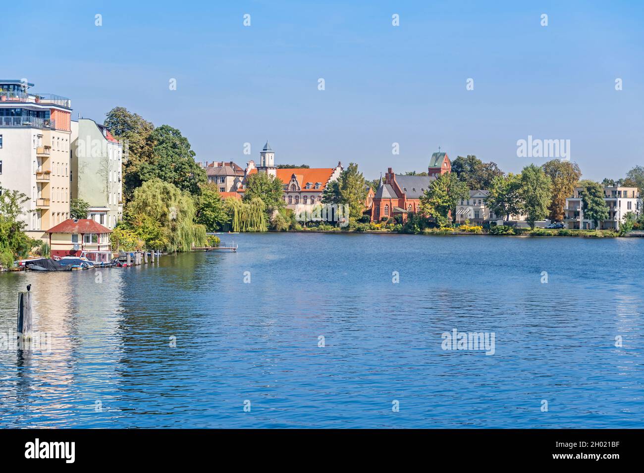 Berlin, Germany - September 6, 2021: River Spree at the confluence with the Dahme and a view at a local area Dammvorstadt with the buildings of a Cath Stock Photo