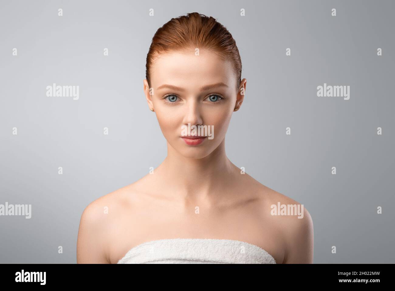 Bodycare For Youth. Pretty Girl With Ponytail Hairstyle Posing Wrapped In White Towel Looking At Camera Standing Over Gray Studio Background, Spa And Stock Photo