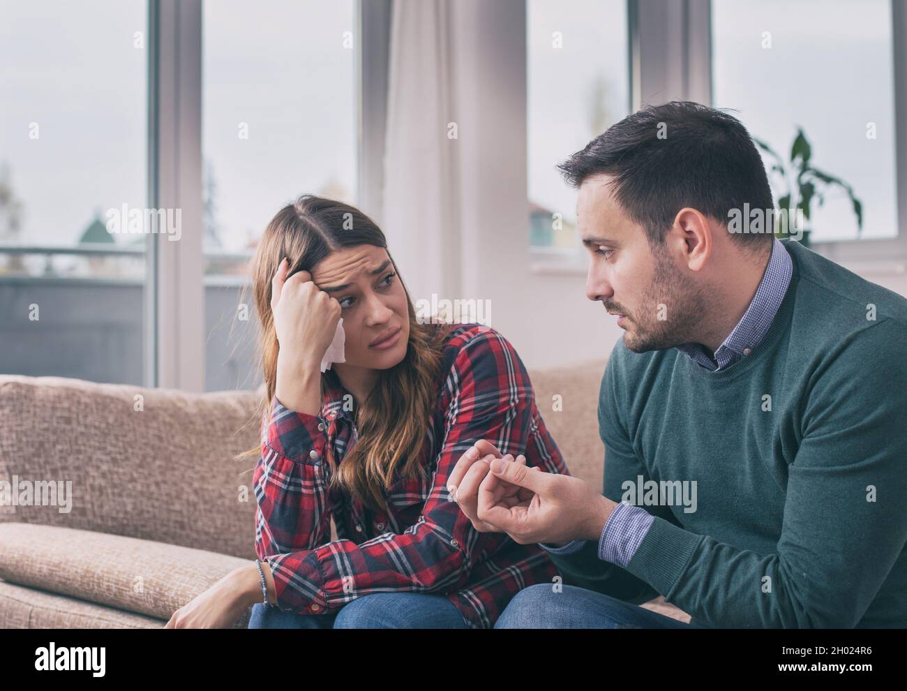 Young couple having fight at home. Girl crying and man explaining ...