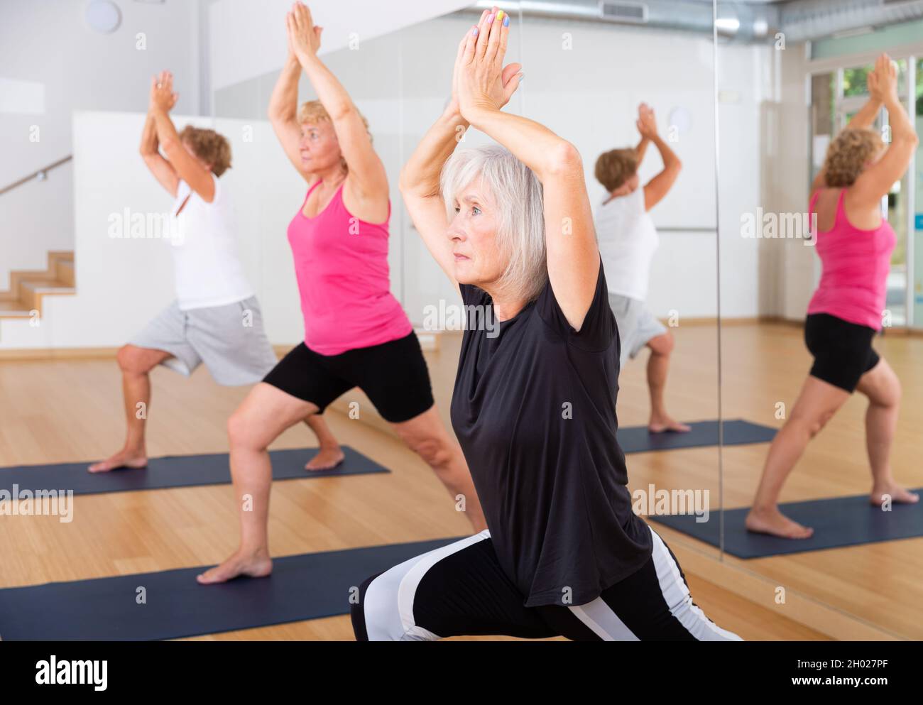 Aged women standing in crescent lunge pose Stock Photo