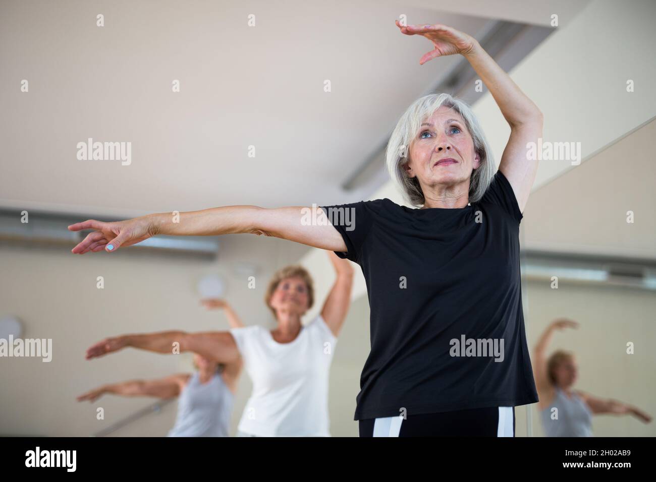Mature woman learning classical ballet technique in choreography class Stock Photo