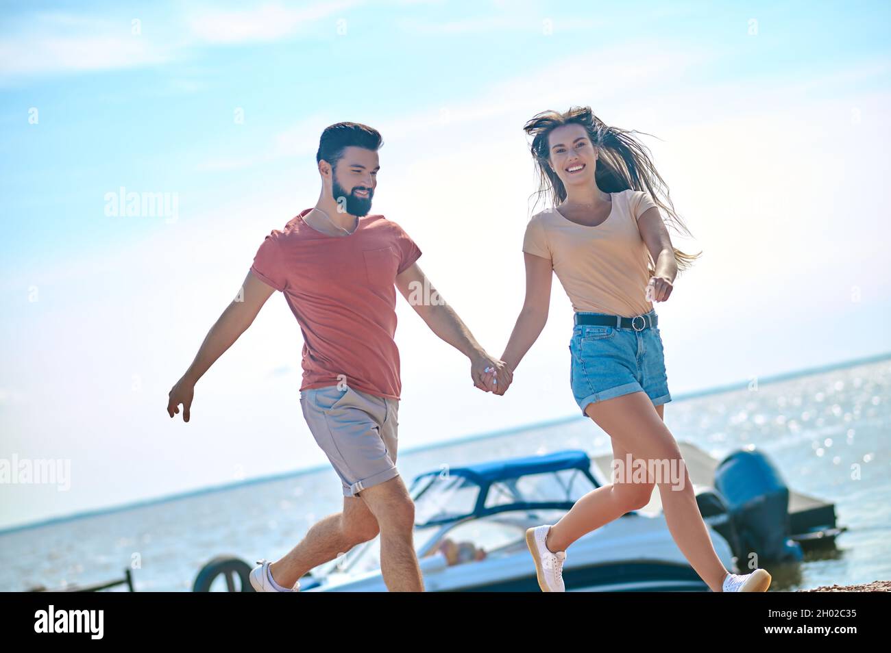 A couple holding hands and running on a beach Stock Photo - Alamy