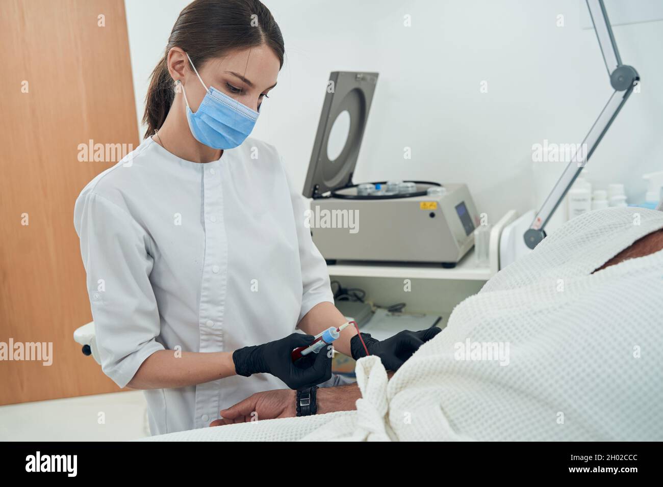 Doctor taking blood sample from patient in clinic Stock Photo Alamy